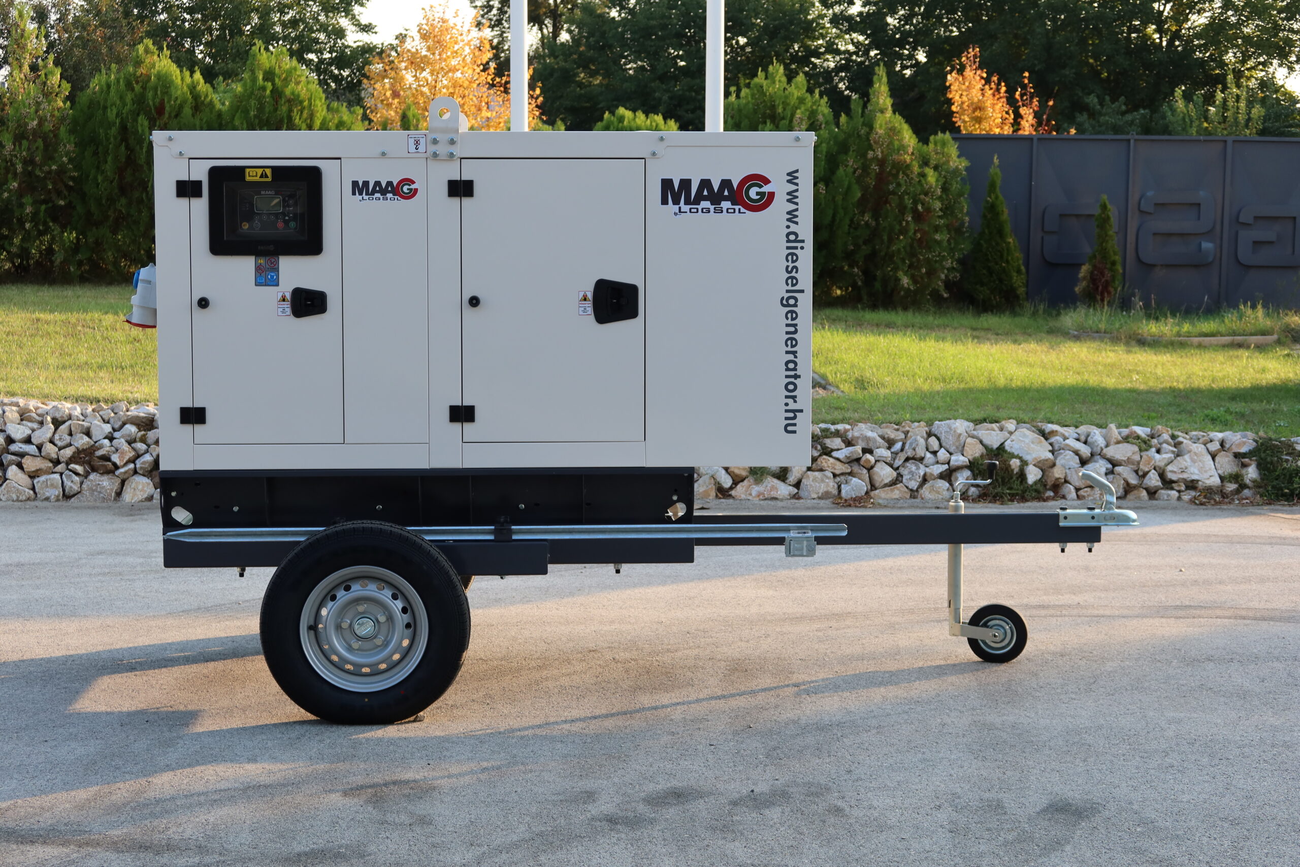 Krém színű, egytengelyes utánfutóra épített mobil MAAG dízelaggregátor oldalnézetből, beépített digitális vezérlőpanellel és a gép oldalán látható www.dieselgenerator.hu felirattal.